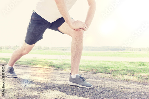 A man performs a warm-up on a sunny morning in the Park, a man is going to run a marathon, copy space, cropped image, toned