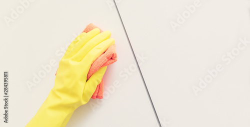 Human in protective gloves cleaning kitchen cabinet, human hands, close up, copy space, toned