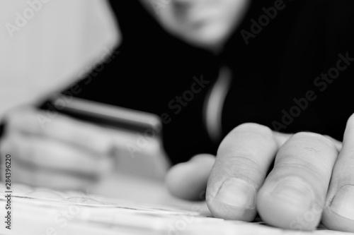 The offender in the house of his victim, man holds a plastic card, the robber steals electronic money, men's hand, closeup, cropped image, black and white toned