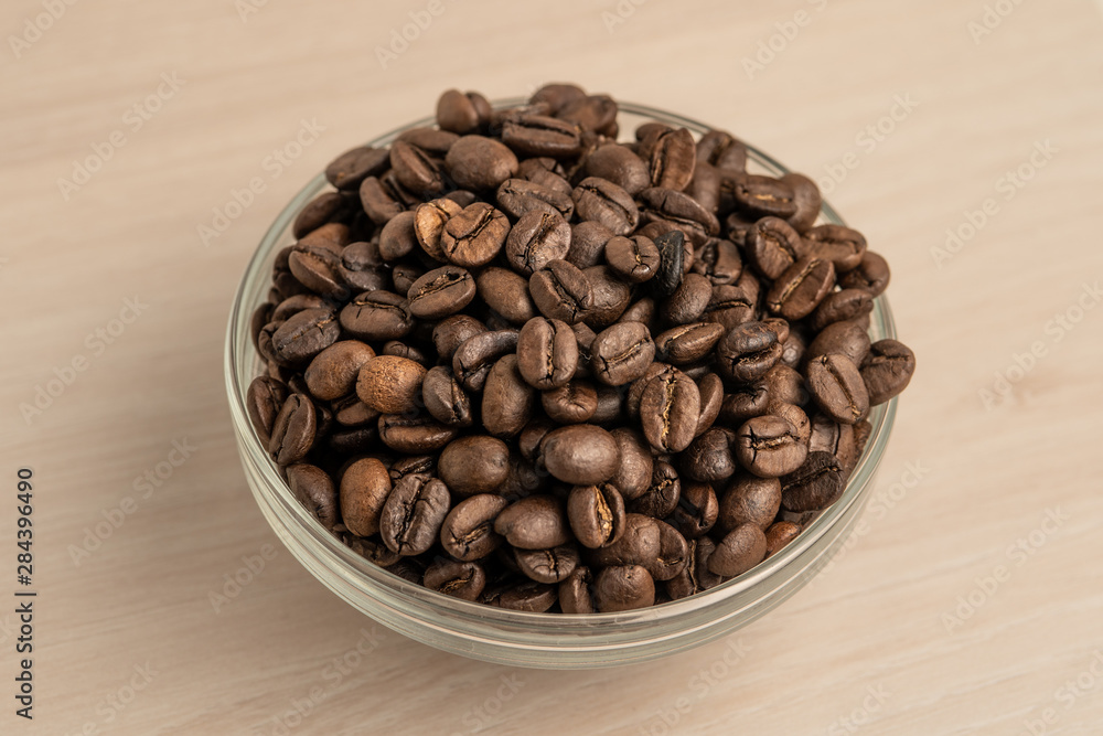 Fototapeta premium coffee beans in a glass bowl on wooden background