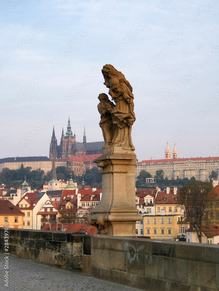 Czech Republic, Prague. A statue of St. Anne, with Prague Castle in the background, is one of thirty on the Charles Bridge in Prague, Czech Republic.