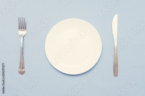 Cutlery set with plate. Dish, fork and knife, blue background, closeup, top view