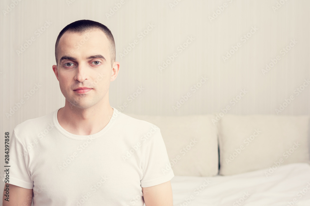 Attractive man sitting on the bed in the bedroom, young man look in the camera, copy space, toned Attractive man sitting on the bed in the bedroom, young man look in the camera, copy space, toned