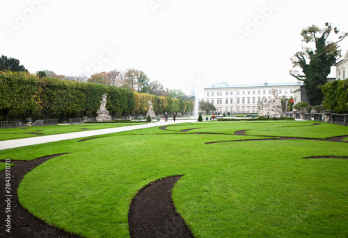 Salzburg, Salzburg, Austria - A peaceful, garden setting with walkways situated in front of an old world building. The area is surrounded by trees.
