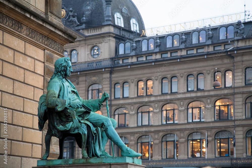 Copenhagen, Denmark - A statue of a man sitting in a chair wearing 18th century clothes is outside a building.