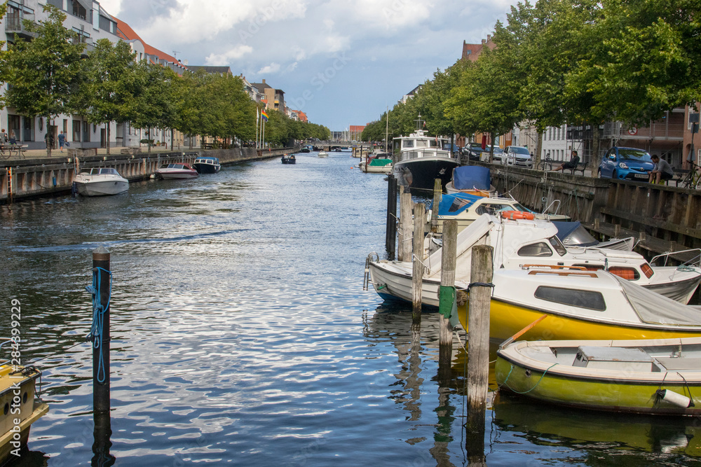 Typical canal in Copenhagen in a residential area lined with homes and personally owned boats.