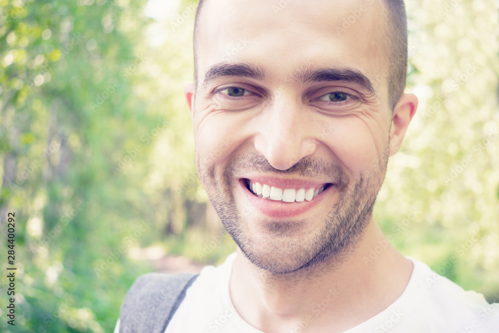 Joyful handsome young man in Park in autumn, attractive man smiling and looking at the camera, portrait, close up, toned Joyful handsome young man in Park in autumn, attractive man smiling and looking at the camera, portrait, close up, toned