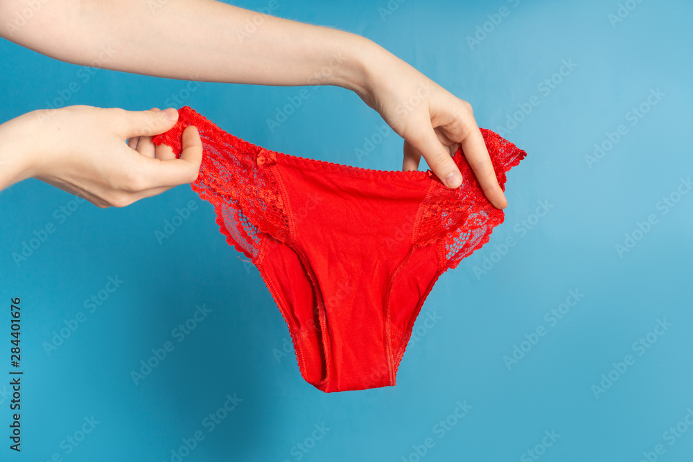 Woman holds red panties on blue background Woman holds red panties on blue background