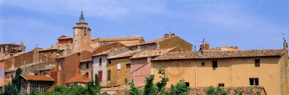 France, Roussillon. The tones of Roussillon buildings-amber, terra cotta and peach-provide a lovely contrast to the calm blue sky, in Provence, France.