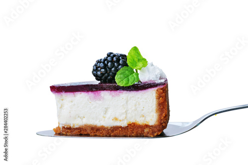 Blackberry cheesecake slice on cake cutter isolated on white. No-bake cheesecake with graham cracker crust, cream cheese filling and blackberry jelly, decorated with whipped cream.