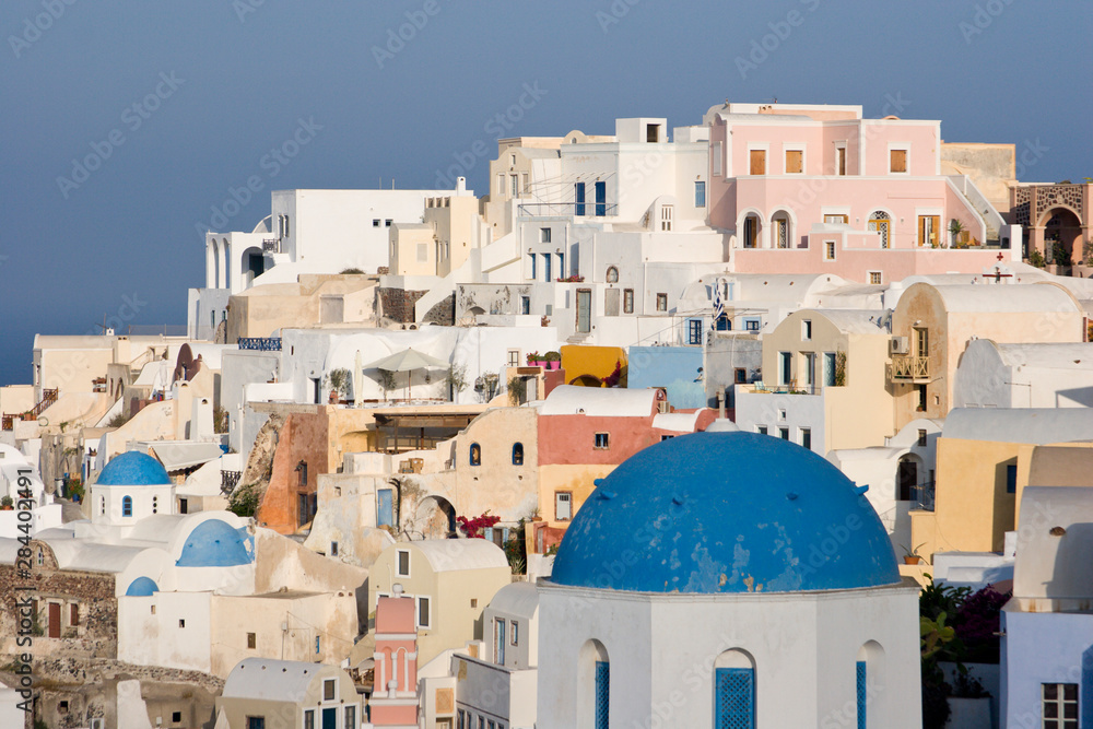 Greece, Santorini, Thira, Oia. Blue dome of Greek Orthodox church with town in the background. Greece, Santorini, Thira, Oia. Blue dome of Greek Orthodox church with town in the background.