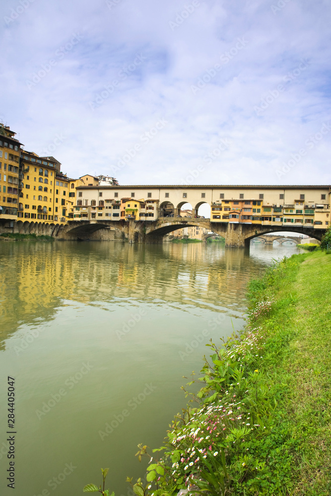 Italy, Florence. Historic Ponte Vecchio bridge is seen from the banks of the River Arno. 