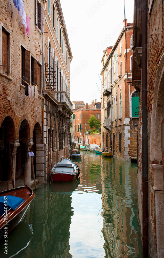 Venice, Veneto, Italy - Buildings surrounded by the canals in Venice, Italy. Boats are parked in the canals.