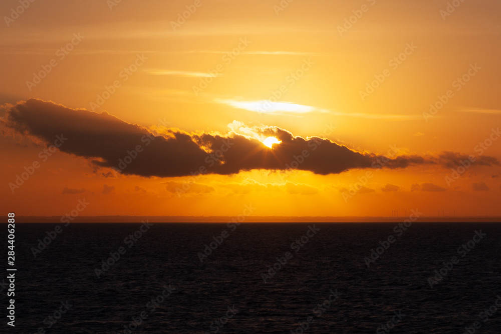 Naklejka premium Sun rising in the clouds during sunset on the Adriatic coast