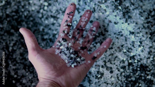 Plastic black and white granules are poured from the hand. Plastic granules, dye, polymer granules are used for the production of plastic products