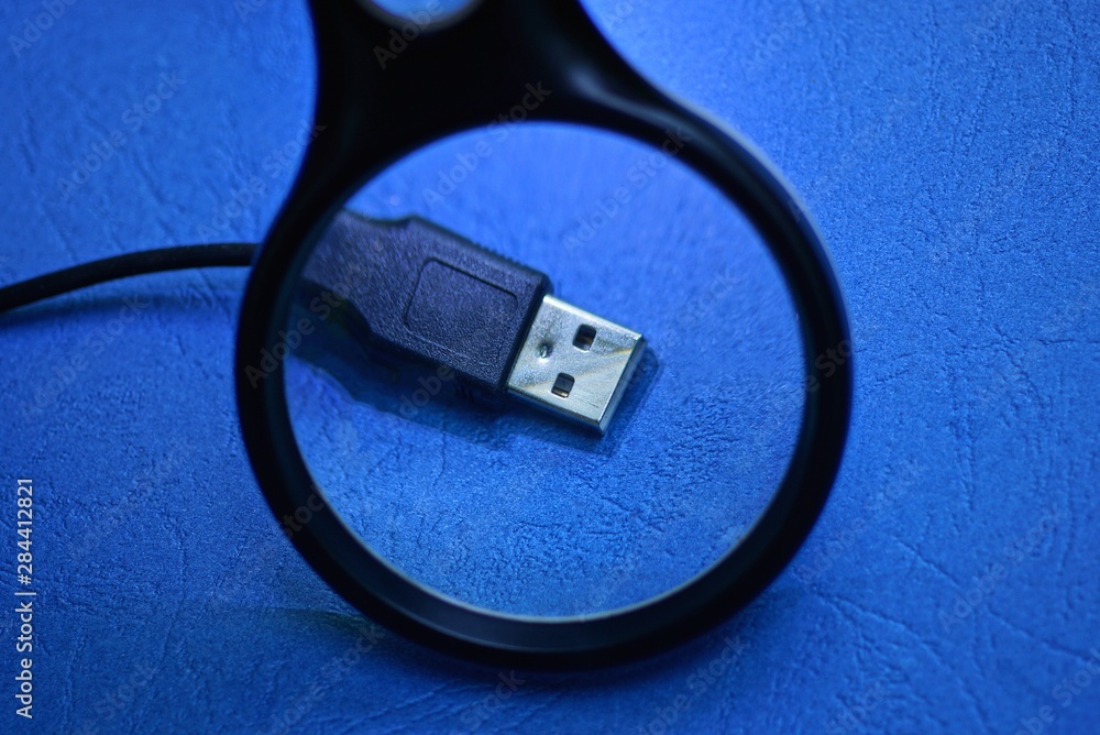 magnifier enlarges black usb cord with plug on blue table magnifier enlarges black usb cord with plug on blue table