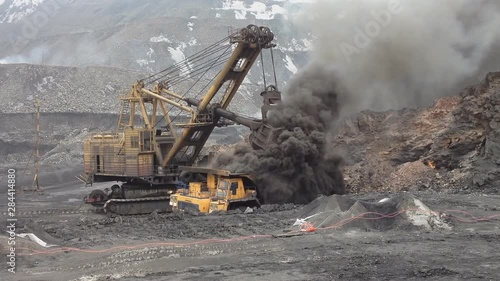 excavator loads a truck burning coal