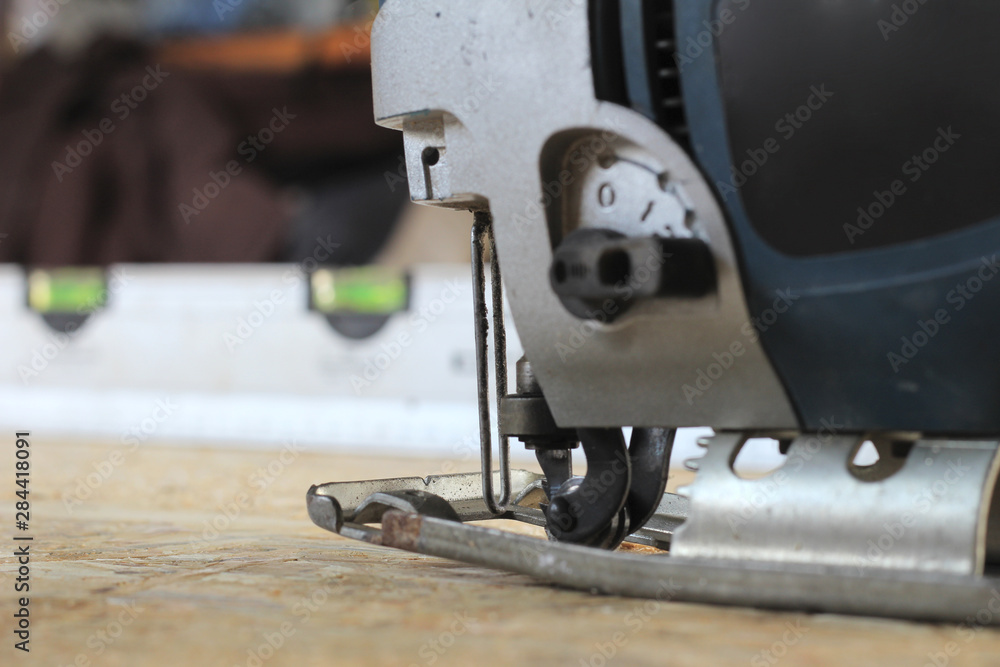 blue-silver electric jigsaw on the osb plate. The process of sawing OSB plywood blue-silver electric jigsaw on the osb plate. The process of sawing OSB plywood