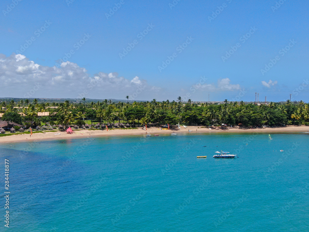 Aerial view of tropical white sand beach, palm trees  and turquoise clear sea water in Praia do Forte, Bahia, Brazil. Travel tropical destination in Brazil