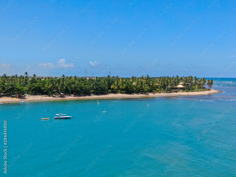 Aerial view of tropical white sand beach, palm trees  and turquoise clear sea water in Praia do Forte, Bahia, Brazil. Travel tropical destination in Brazil