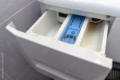 Dirty moldy washing machine detergent and fabric conditioner dispenser drawer compartment close up. Mold, rust and limescale in washing machine tray. Home appliances periodic maintenance