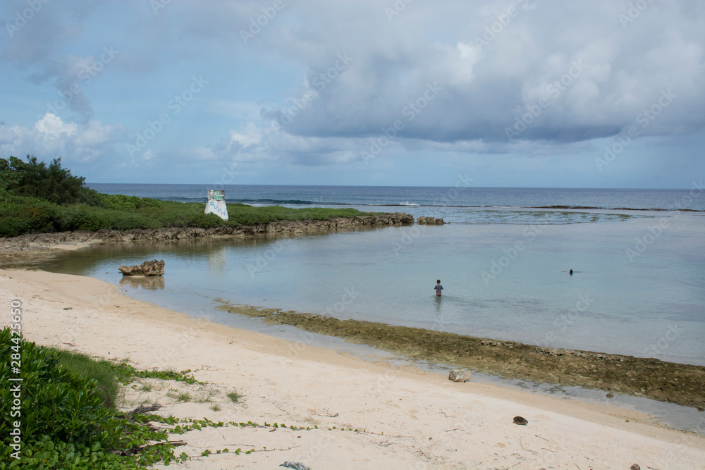 Micronesia, Mariana Islands, US Territory of Guam, Talofofo. Southern Guam, young boy on beach in shallow cove.