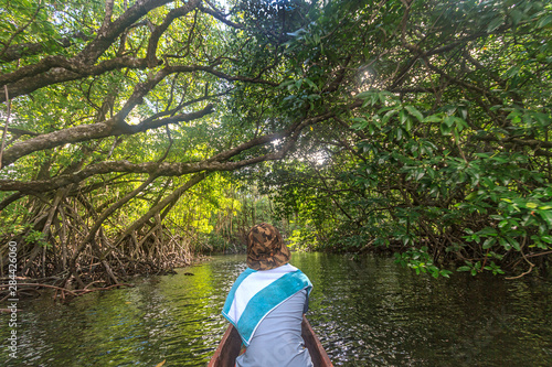 Kosrae  Micronesia. Woman vsitor sitting at the bow of a hand carved outrigger canoe for a trip through the mangrove tree lined channels of the Utwe Biosphere Reserve.