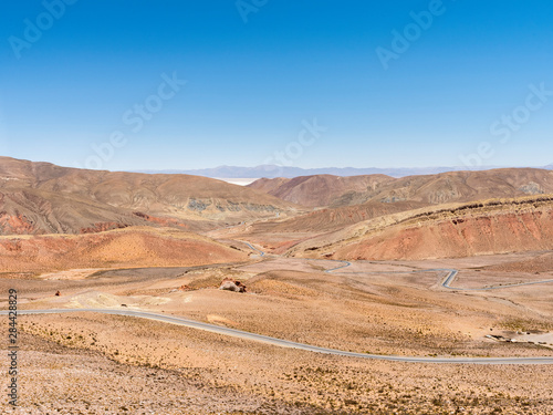 View from mountain pass Abra de Potrerillos, Salar in the background. Landscape near Salinas Grandes salt flats in the Altiplano, Argentina.