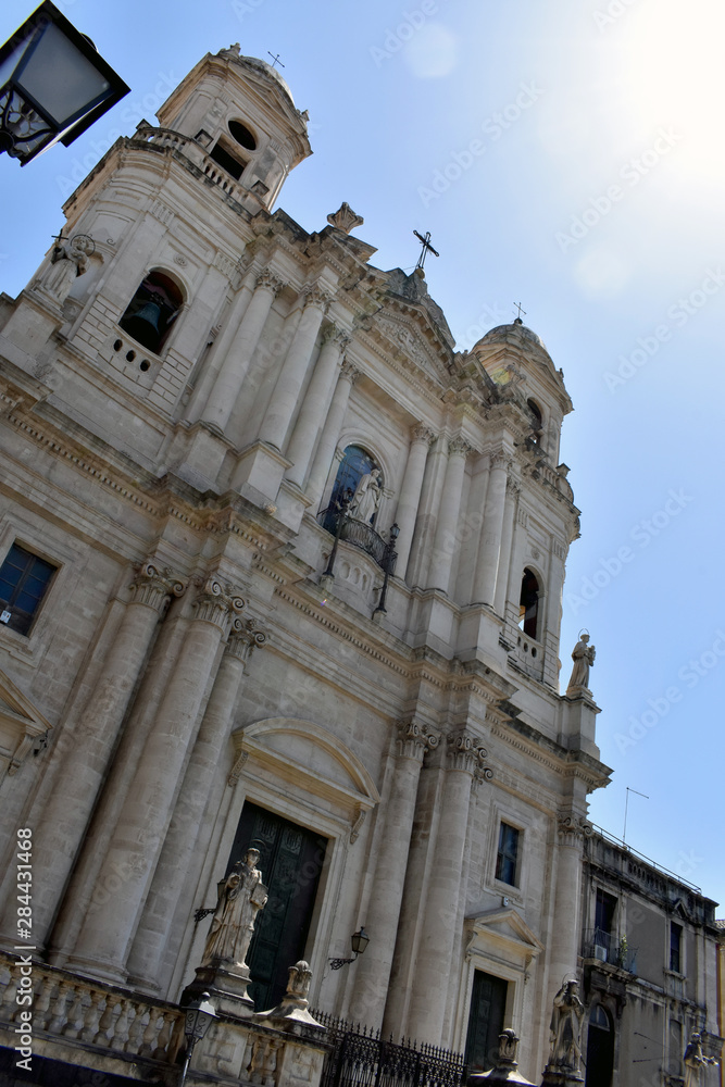 Upward view of the facade of the Catania baroque church of Saint Francis of Assisi to the Immaculate with bright sun and blue sky in the background