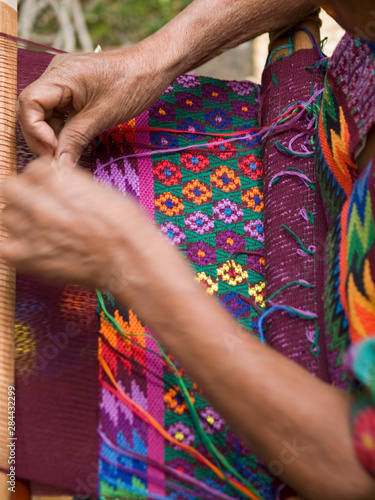 Antigua, Guatemala. A weaver in indigenouos dress at work.