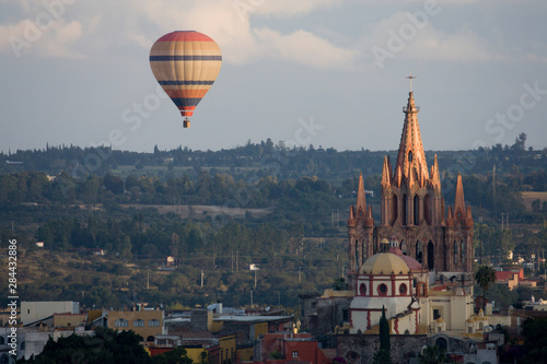 Mexico, San Miguel de Allende. Hot air balloon drifting past La Parroquia Cathedral.