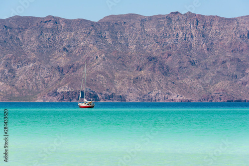 Mexico, Baja California Sur, Sea of Cortez, Loreto Bay. Lone sailboat on flat calm water with Sierra de la Giganta beyond