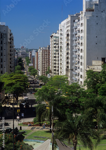 Uruguay, Montevideo, sun-washed while buildings line a bisy residential street with a view to the national Capitol building.