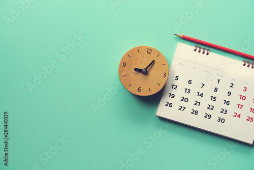 close up of calendar and alarm clock on the green table, planning for business meeting or travel planning concept