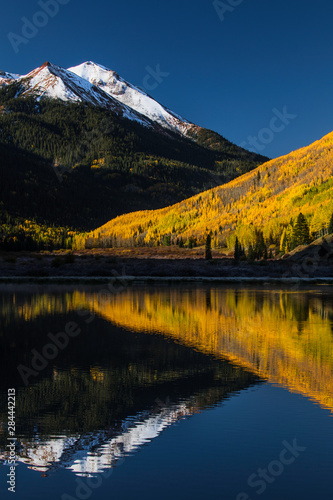 Fall colors and Red Mountain reflected on Crystal Lake at sunrise, near Ouray, Colorado