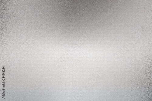 Glowing silver foil metallic sheet with scratched surface, abstract texture background