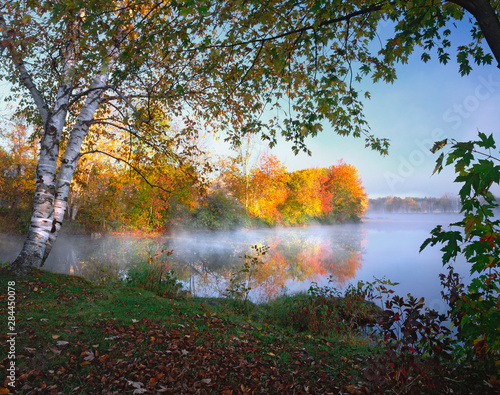 USA, Maine, Pittsfield. Morning sun and fog rising from Douglas Pond.  photo