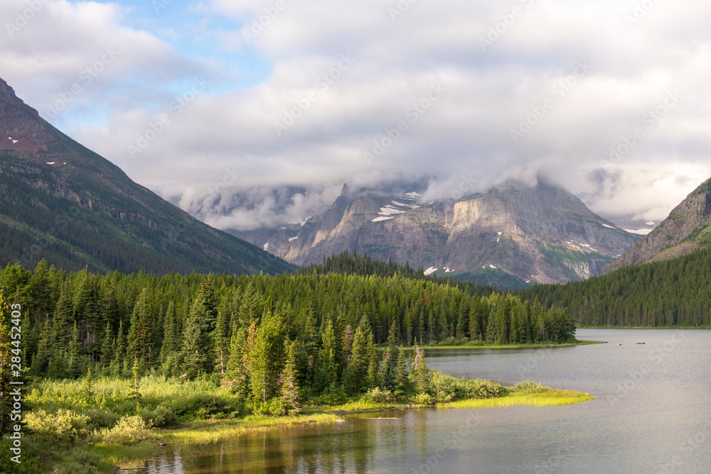 USA, Montana, Glacier National Park. Morning light on Swiftcurrent Lake with peaks cloud covered.