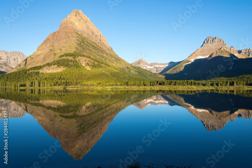 US, MT, Glacier National Park. Glass calm on Swift current Lake reflects Grinnell Point and Mt Wilbur, photo