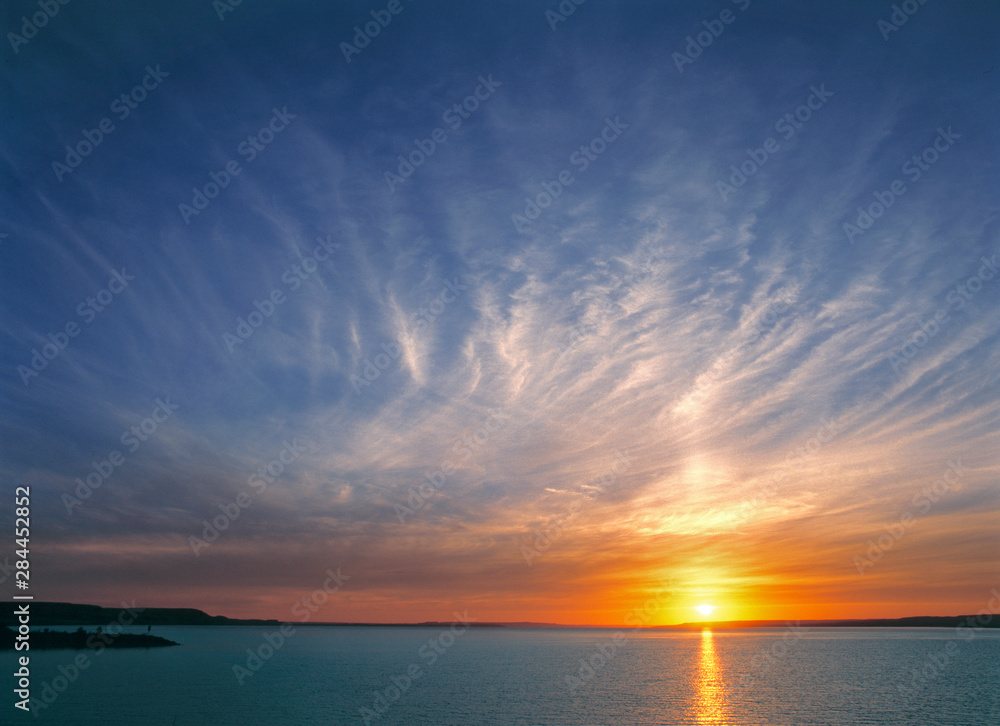 USA, North Dakota, Lake Sakakawea. Cirrus clouds take on the colors of the sun setting over Lake Sakakawea, in North Dakota. USA, North Dakota, Lake Sakakawea. Cirrus clouds take on the colors of the sun setting over Lake Sakakawea, in North Dakota.