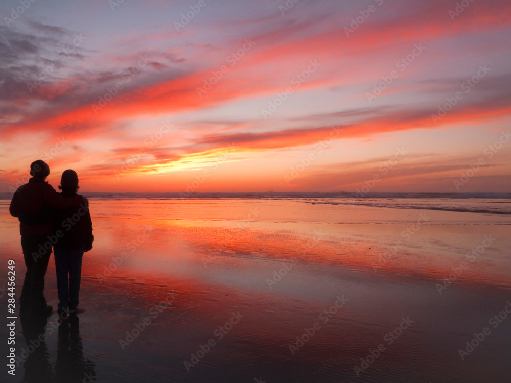 USA, Oregon, Cannon Beach. Couple contemplates the sunset. (MR)
