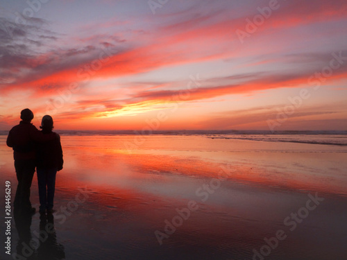 USA, Oregon, Cannon Beach. Couple contemplates the sunset. (MR)