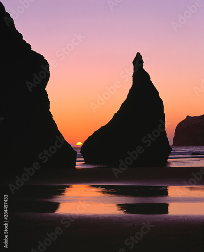 USA, Oregon, Face Rock Wayside. The sun sets between two sea stacks at Face Rock Wayside on the southern Oregon coast.