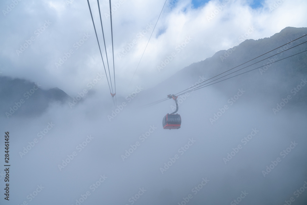 The cable car to mountain top with low clouds and mountain view