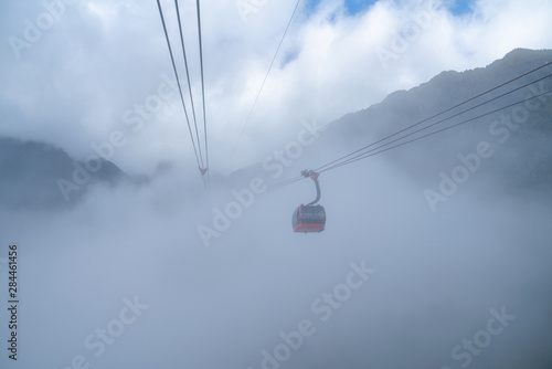 The cable car to mountain top with low clouds and mountain view