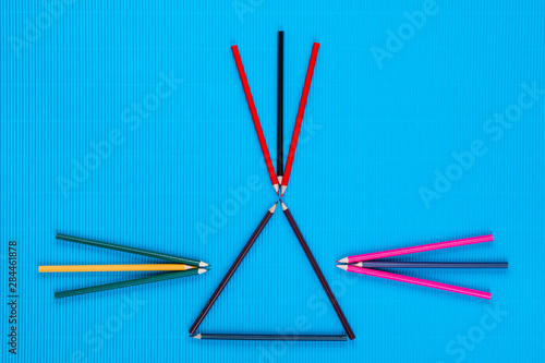 A bunch of crayons forming arrows on an blue background, shot from above.