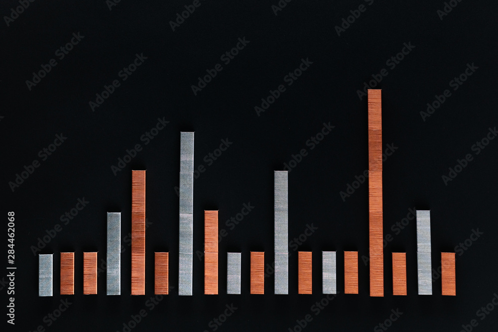A graph made with staples on a black background , shot from above. A graph made with staples on a black background , shot from above.