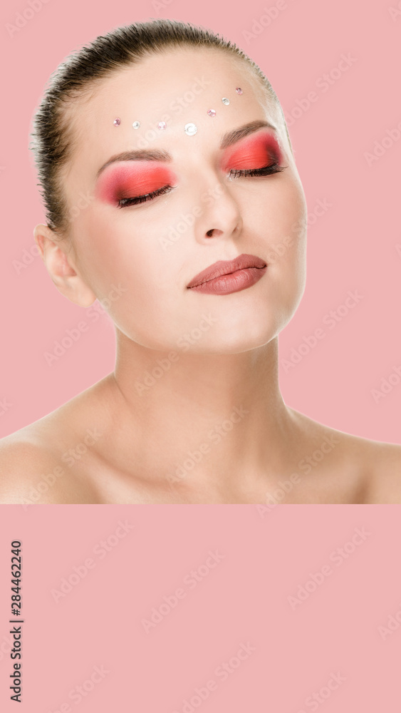 Beauty portrait of attractive model's face with bright rhinestones visage, on pink background. aspect ratio and vertical position convenient for placement on a smartphone Beauty portrait of attractive model's face with bright rhinestones visage, on pink background. aspect ratio and vertical position convenient for placement on a smartphone