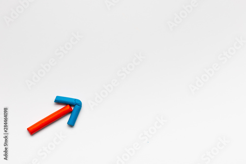 An arrow pointing upwards made from chalk on white background, shot from above.