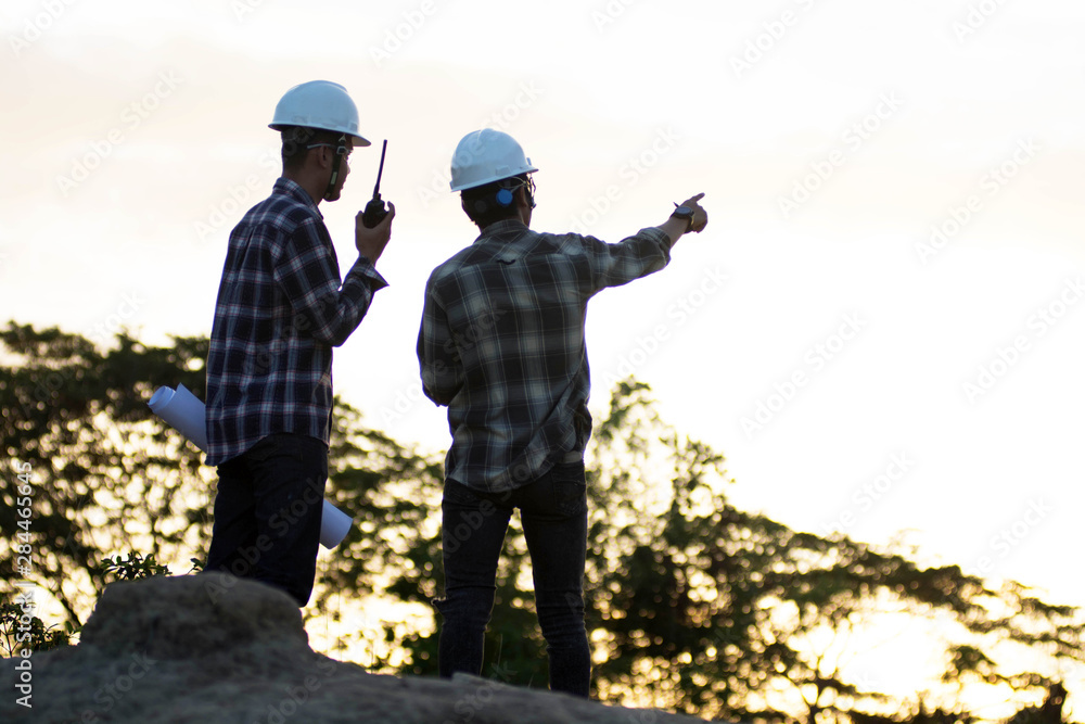 Blurry silhouette portrait of two engineers or architects pointing at the golden sky Blurry silhouette portrait of two engineers or architects pointing at the golden sky